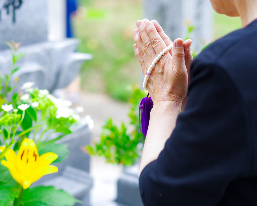 お墓の前で手を合わす、お墓参りの写真